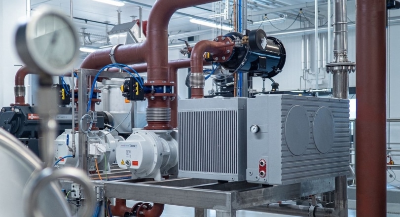 Commercial boiler room with pumps, piping and a pressure gauge
