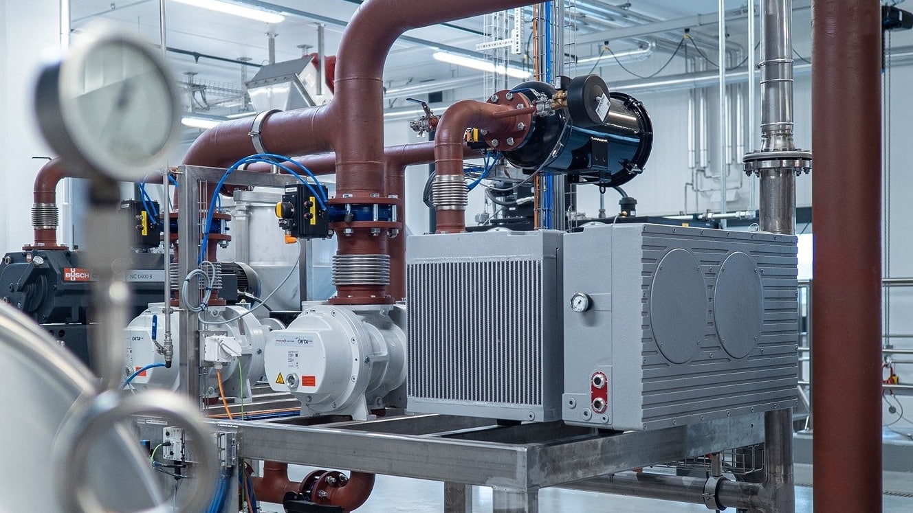 Commercial boiler room with pumps, piping and a pressure gauge