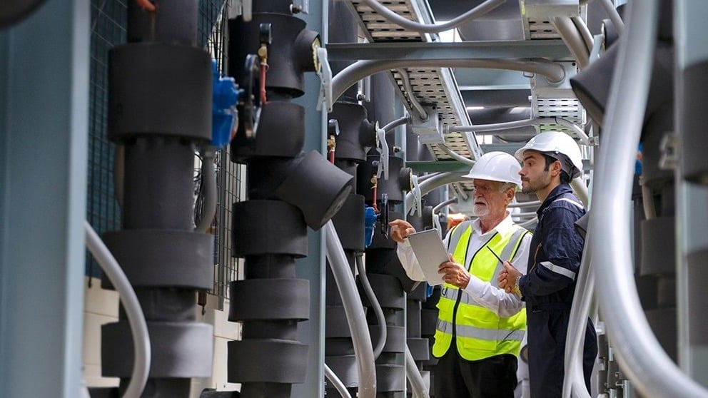 Technicians reviewing plans beside commercial boiler equipment