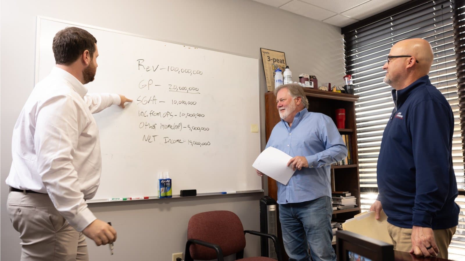 Three Georgia Mechanical team members talking at a whiteboard in an office